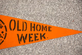Close-up of the vintage orange felt banner, showcasing black stencil lettering for 'OLD HOME WEEK.'