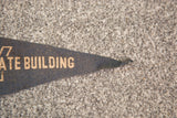 Worn, curled tip of vintage dark blue felt flag banner with faded light lettering.