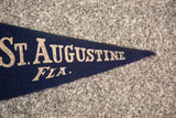 Vintage felt flag with cream 'AUGUSTINE FLA.' text on navy blue, right end.