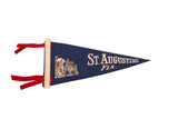 Vintage navy blue felt St. Augustine pennant flag with red ties and building graphic.