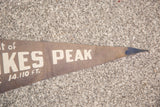 Pointed end of vintage Pikes Peak felt flag, cream 'PEAK' text, dark blue tip.