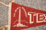Red felt vintage banner showing cream edge binding and 'SAN JACINTO' monument text.