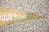 Pointed tip of vintage Henry Ford Museum felt flag with white text and discoloration.