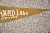 Pointed end of the vintage green felt Newfound Lake banner, showing cream text and wear.
