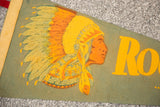 Vintage felt flag graphic: feathered headdress profile, 'Ro' text, in yellow, orange, and green.