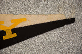 Black and tan felt flag banner tip with yellow applique and visible zigzag stitching.