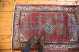 Mir Serbend rug corner featuring distressed red field and geometric blue and ivory border.
