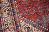 Textural red field with subtle botehs, framed by the ornate mirror Serbend border.