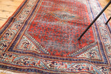 Distressed red rust field, blue and ivory Mir Serbend border, and visible fringe on vintage rug.