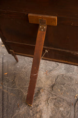 Detail of the vintage Kiwanis wooden display stand's hinge and worn leg.