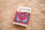 Miniature Heriz design rug coaster with a cherry red field and ornate blue medallion.