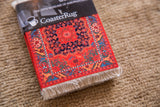 Stacked coasters with vibrant red, blue, and gold Northwest Persian rug design and white fringe.