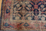 Distressed antique Malayer rug corner with blush red border and indigo Herati motifs.