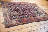 Distressed antique Malayer rug showing indigo Herati motifs, blush red border, and fringe.