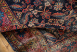 Distressed antique Malayer rug fold, showing rich blush red Herati motifs on indigo.