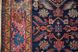 Close-up of distressed Malayer rug's indigo field with serrated leaves, pinwheels, and blush border.