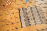Vintage Scandinavian rag rug showing charcoal end, varied ivory, beige stripes, and light tatter.