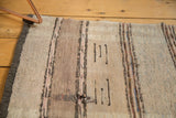 Handwoven rag rug texture showing varied ivory, beige, blue stripes and light tatter.