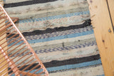 Distressed character and varied blue, ivory, charcoal stripes of a vintage rag rug.