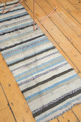 Detail of hand-woven Scandinavian rag runner showing distressed blue, ivory, and charcoal stripes with textural abrashes.