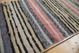Textured vintage Scandinavian rag rug with varied blue, blush, and neutral stripes.