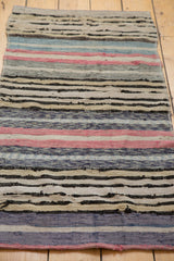 Hand woven texture of vintage Scandinavian rag rug, featuring colorful horizontal stripes and light tatter.