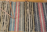 Textured stripes of a vintage Scandinavian rag rug in ivory, charcoal, blue, and faded pink.