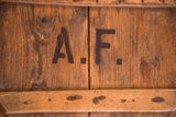 Vintage wooden pizza board detail: stamped A.F. initials, rustic wood grain, and hand-hewn nails.
