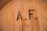 Vintage wooden board with dark stenciled 'A.F.' initials and rustic patina.