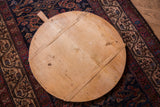 Rustic vintage wooden pizza board showing grain, knots, and warm aged patina.