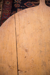Vintage wooden pizza board's aged surface, natural grain, central seam, and handmade marks.