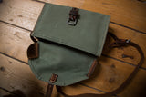 Open vintage Swiss Army bag revealing green canvas and brown leather trim.