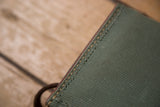 Close-up of vintage Swiss Army bag's sturdy olive fabric, contrasting stitching, red trim.