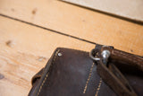 Vintage dark brown leather messenger bag with stitching, metal rivet, and embossed S.