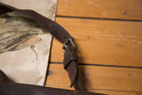 Dark brown aged leather strap and silver buckle detail of the vintage messenger bag.