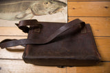 Distressed dark brown leather side of a vintage messenger bag with visible stitching and strap.