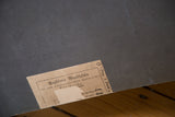 Vintage fish chart back detail: gray surface with a worn beige label and handwritten marks.