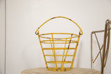 Small vintage mustard yellow metal egg basket with chippy paint and rust.