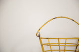 Mustard yellow metal handle with chipped paint and rust on the vintage egg basket.