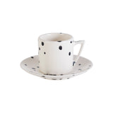 Handmade modern white espresso cup and saucer with irregular black spots.