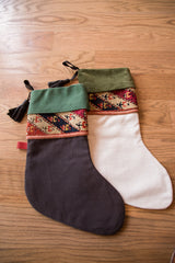Charcoal heirloom stocking with green suede cuff, geometric antique rug fragment, and black leather tassel.