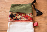 Olive suede cuff, patterned antique rug fragment, ivory linen, and black leather tassel.
