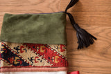 Luxurious green suede cuff, geometric antique rug fragment, and black leather tassel.