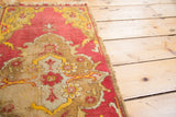 Scalloped medallion of antique Yastik rug, saffron yellow, brick red, distressed texture, tattered edge.