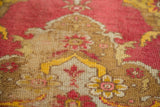Distressed texture of an Antique Yastik rug, showing saffron yellow, brick red, and wooded tones.