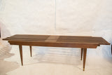 The MCM slat bench showing extended slats and tapered legs with brass caps.
