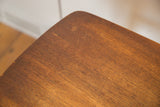 MCM Danish teak end table corner, showing vintage wear, scratches, and wood grain.