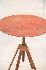 Patina on the red metal top and swivel base of the vintage industrial table.
