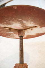 Underside view of the vintage industrial table, showing rusty pole connection and swivel.