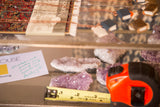 Purple amethyst crystal clusters with a yellow measuring tape, emphasizing size and raw texture.